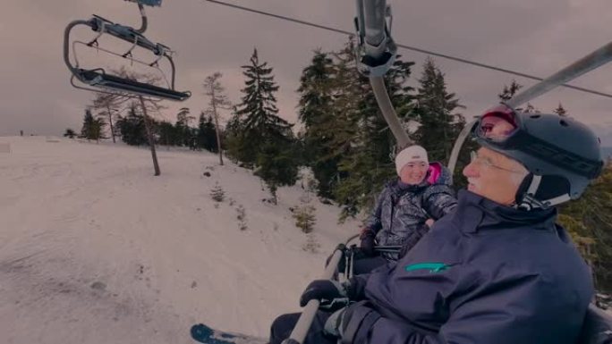 带着女儿在滑雪缆车上的老人，在冬天欣赏大自然的景色