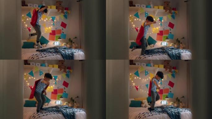 快乐的小男孩穿着戏服跳上床在家里五颜六色的卧室里玩游戏享受嬉戏的想象力