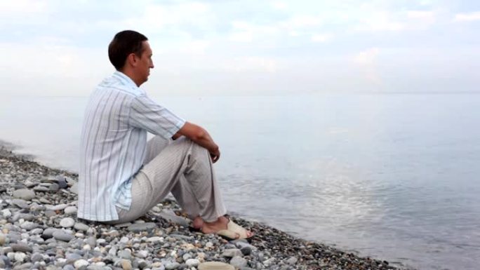 坐在卵石海岸上的人看着大海