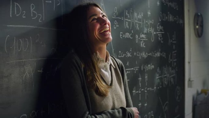教室里快乐的年轻女老师的肖像躺在黑板上，带着数学公式，微笑着。科学研究人员获得赠款，对新的机会感到兴