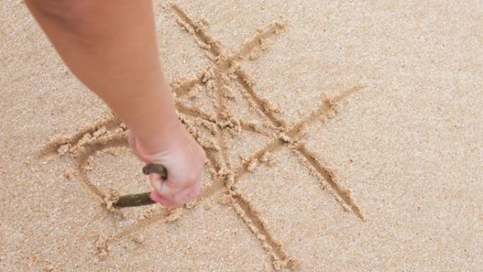 女孩在沙滩上手绘井字。