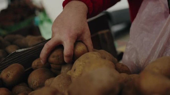 一个在市场上选择原始农场有机土豆的人