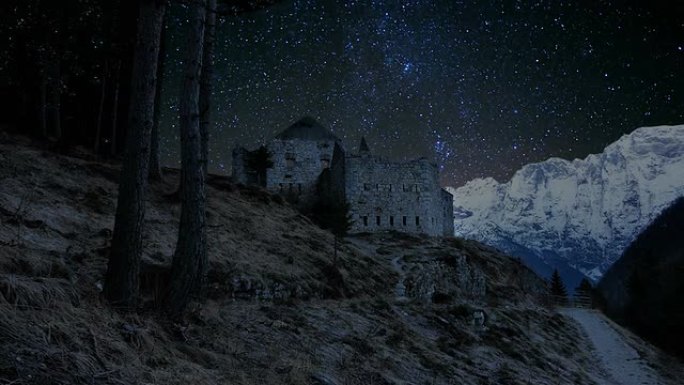 时间推移-惊人的夜空与一条路径通往一个石头建筑废墟。背景是美丽的白雪覆盖的阿尔卑斯山