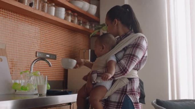 年轻的母亲抱着婴儿在家里清洁厨房工作，照顾婴儿享受母亲的母亲