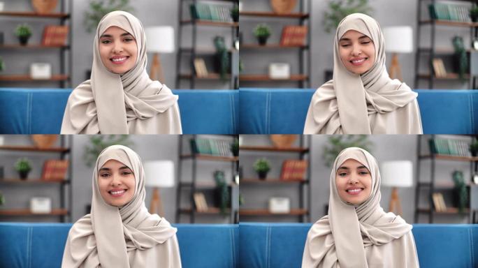 肖像年轻穆斯林妇女米色头巾在现代家庭室内微笑在沙发上摆姿势