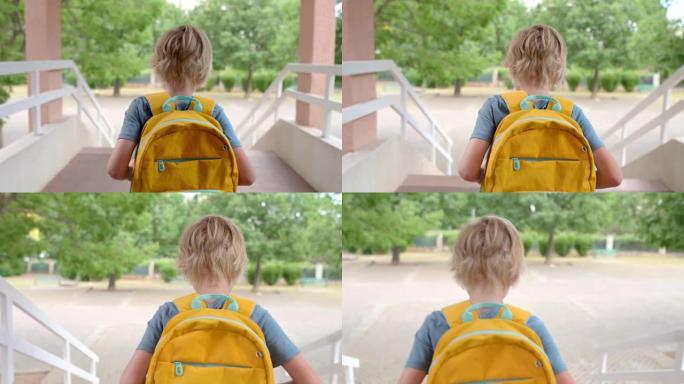 一名小学生从学校走了出来。一个男孩放学后走下楼梯到院子。小学生课后。