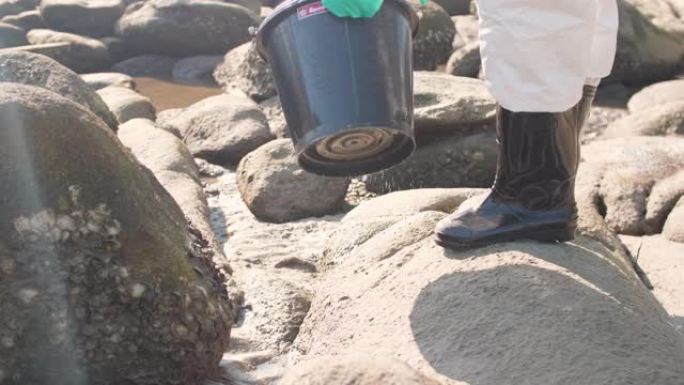 污染控制小组用刷子清洁海滩岩石上的油污