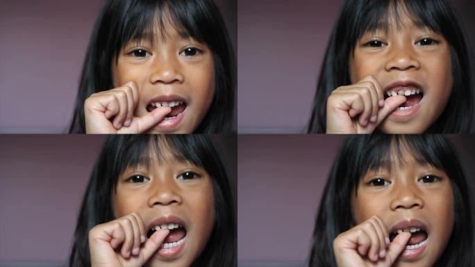 亚洲女孩扭动她的第一个松动的牙齿-特写