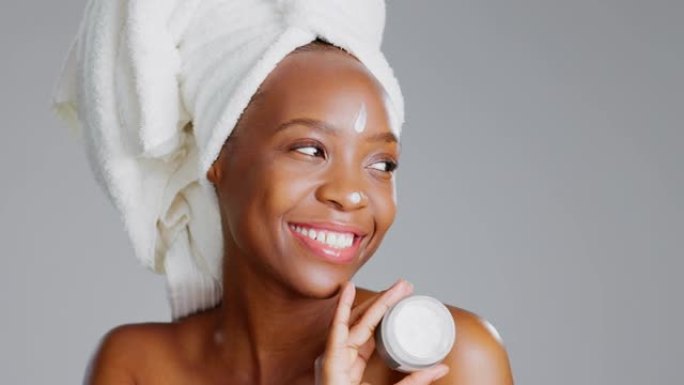 面部，面霜和美容与一个模特黑人妇女在工作室的灰色背景下进行护肤治疗。肖像、毛巾和乳液产品，有吸引力的