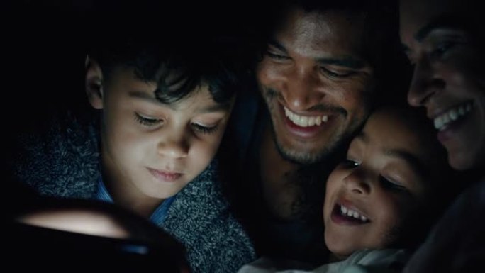 家庭晚上使用平板电脑孩子在触摸屏上玩游戏，父母教孩子在睡觉前看娱乐娱乐