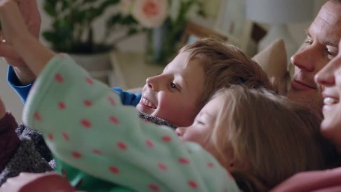带孩子的幸福家庭视频聊天使用智能手机在屏幕上挥舞，在家中享受手机通讯