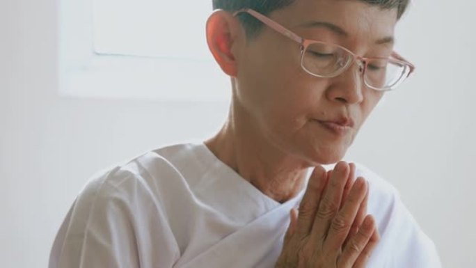 穿着白色礼服的老年人的例行程序一起向佛陀祈祷，退休人员的早晨例行程序。