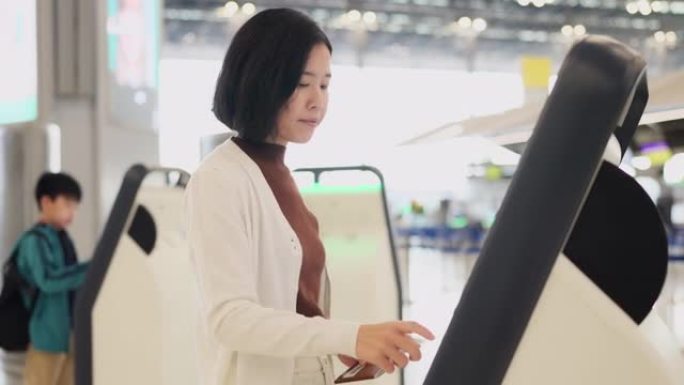 现代技术使旅行变得方便和高度安全。亚洲女性使用自动登机亭机在机场创建登机牌。夏季学校假期旅行。探索经