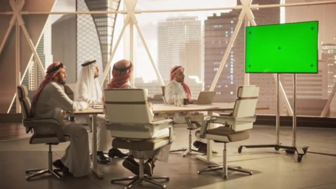 中东高管和管理层与一个远程国际办公室进行会议视频电话。商人在电视上观看带有绿屏模拟显示的演示文稿。