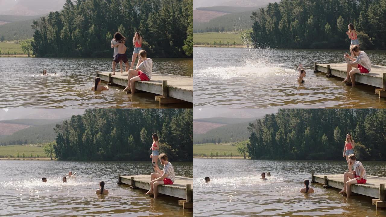 年轻男子抓住女人和她一起在湖中跳跃，在水中泼水一群朋友在夏天的下午闲逛，享受假期
