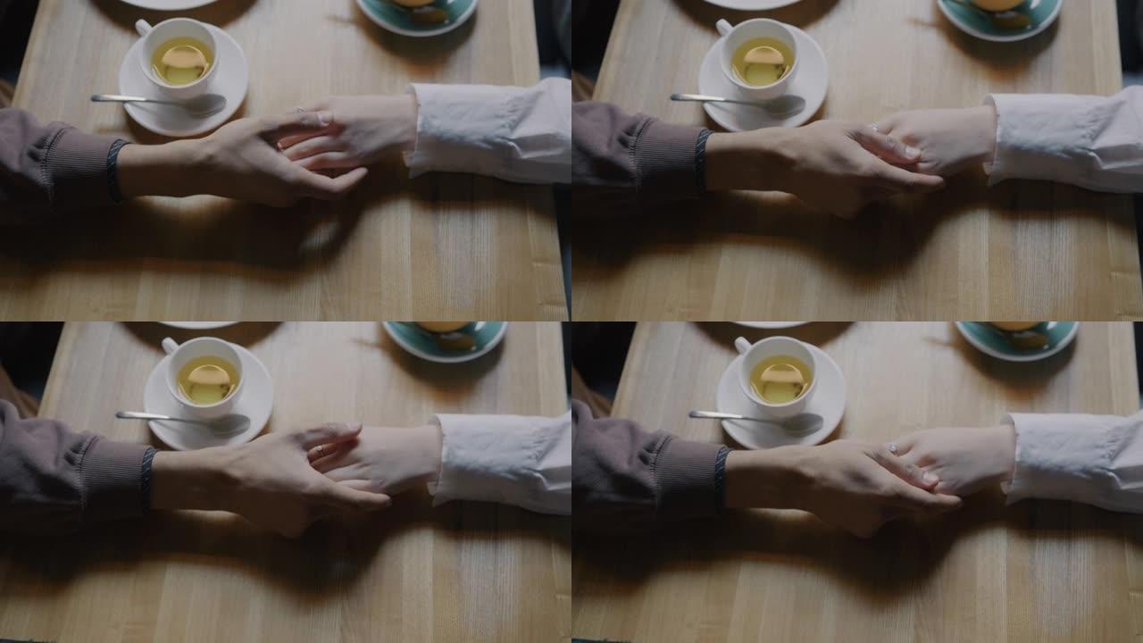 咖啡馆午餐时男性手握爱抚女性手表达爱的高角度视图