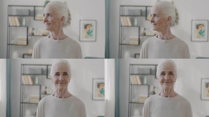 在公寓里，美丽的老年妇女在室内带着幸福的微笑转向相机的慢动作肖像