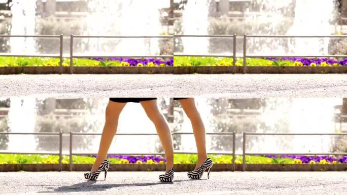 穿着高跟鞋的性感女性双腿在喷泉旁行走。