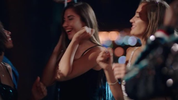 一群朋友庆祝性感的女人跳舞，享受迷人的新年前夜派对，在晚上的屋顶社交聚会上穿着时尚的时尚庆祝活动