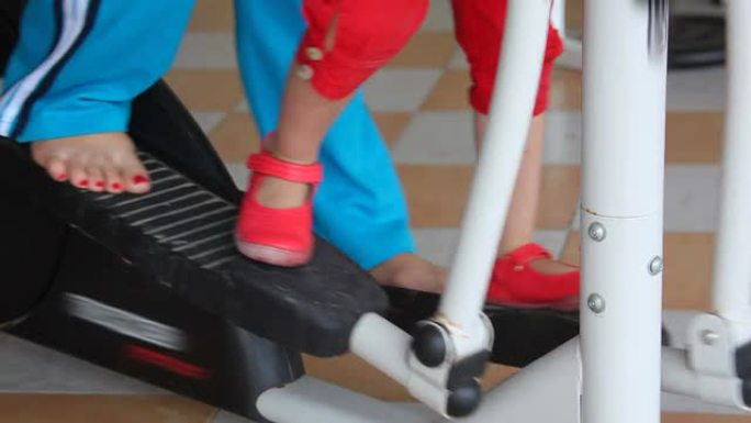 在健身器材上训练的女人和小女孩的腿