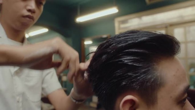 亚洲理发师用定型粉定型客户的头发