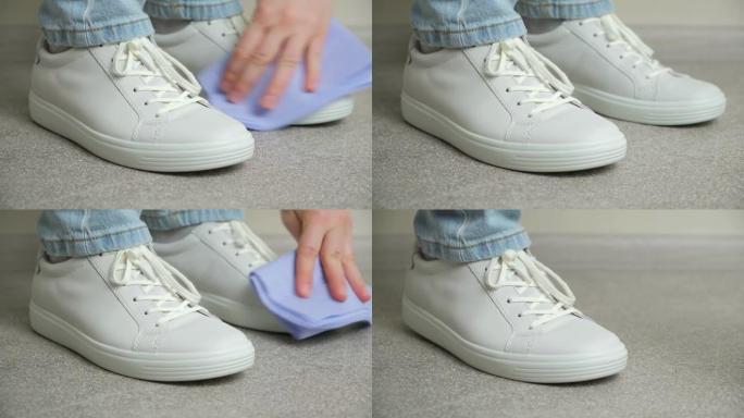 一名妇女用抹布清洁白色皮革运动鞋，清除灰尘，向前迈出一步