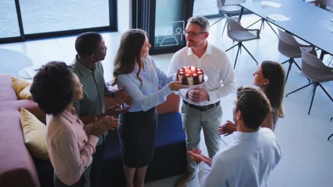 员工在多元文化开放计划办公室用蛋糕庆祝男同事的生日