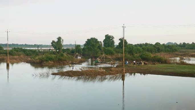 渔民从一个带有中国渔网的小型木制平台将网撒到池塘中
