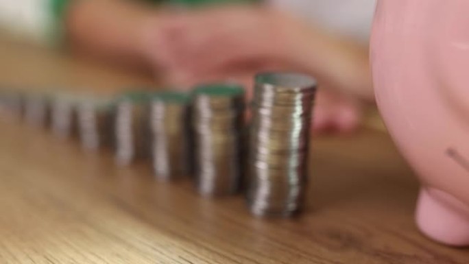 陶瓷存钱罐站在桌子上堆叠的硬币附近
