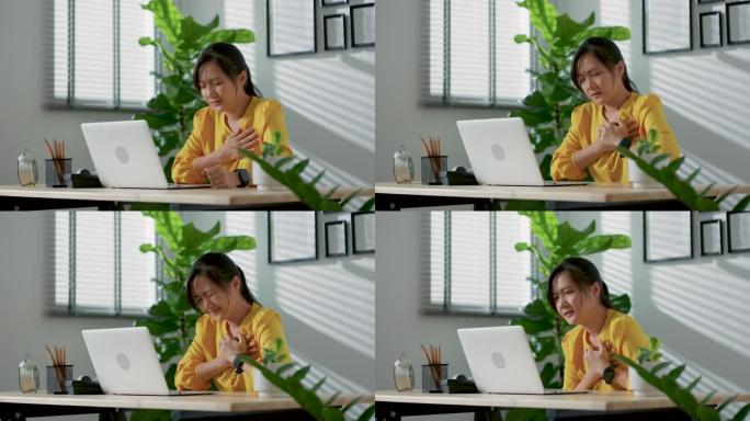 坐在家庭办公室的笔记本电脑上患有胸痛的亚洲女性。