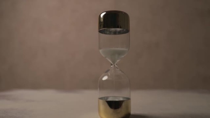 沙漏作为时间压力的项目视频，说明了时间在棕色背景前滴答作响的概念