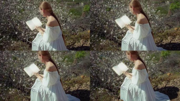 女人在户外看书。盛开的樱桃树。手握乳品的女孩的特写镜头。花朵模糊的背景。
