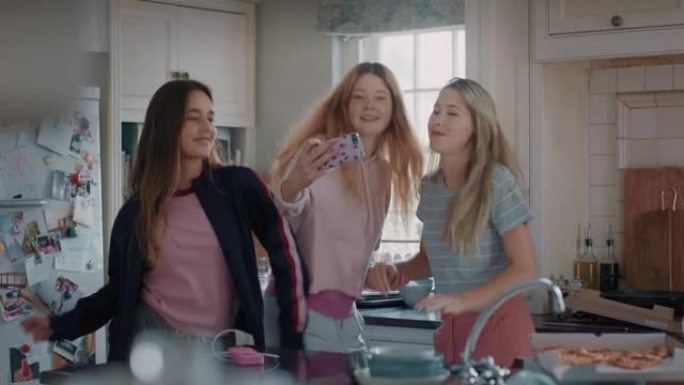 快乐的十几岁的女孩用智能手机拍照，摆姿势做鬼脸，享受一起在社交媒体上分享友谊