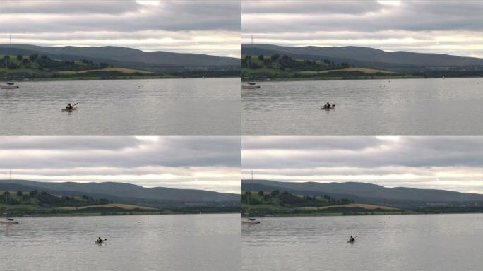孤独的皮划艇手在平静的河上划入远处