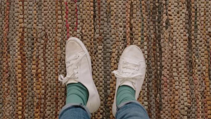 顶视图女人穿着白鞋，站在地毯上享受时尚的新鞋