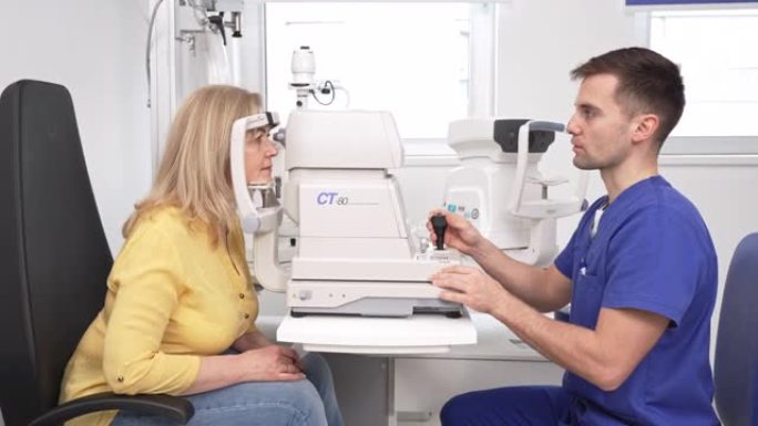 男性眼科医生在诊所检查高级女性患者的眼睛