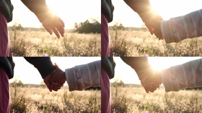 幸福家庭理念。双手握着，在自然背景下日落时母子女儿的结合，4K。幸福家庭、爱情、夫妻、父母、蹒跚学步