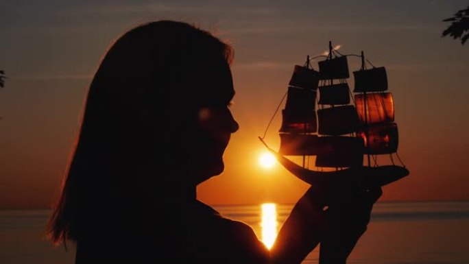 一个带着玩具帆船在夕阳下的女人的侧写