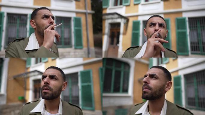 一个沉思的认真的年轻中东男子在外面抽烟，表情沉思。沉思时跟踪镜头特写镜头