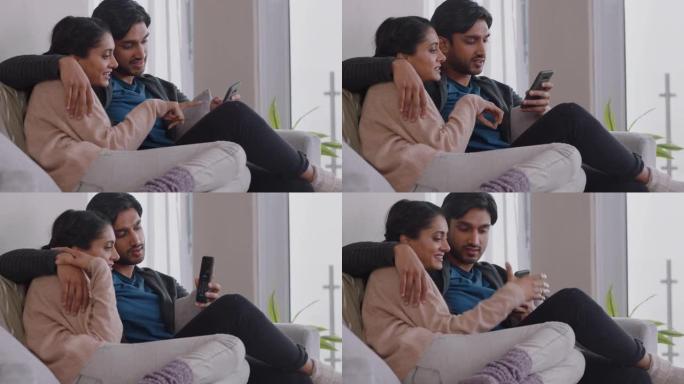 幸福的夫妇在家放松，一起使用智能手机在线购物，享受在沙发上浏览互联网放松