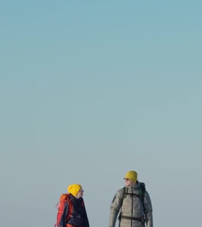 两个背着背包的游客穿过雪场。慢动作