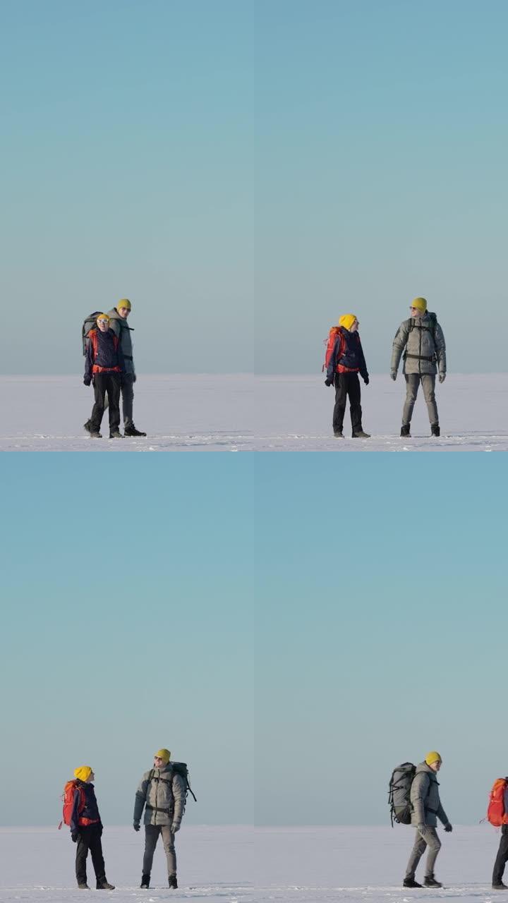 两个背着背包的游客穿过雪场。慢动作