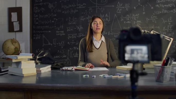 教室里年轻女教师的肖像在黑板前用数学公式远程上课。科学教授在线教学，为她的学生创建电子学习内容