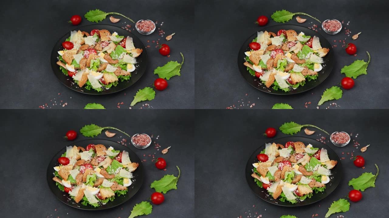 凯撒沙拉配鸡肉，生菜叶，樱桃番茄，磨碎的帕尔马干酪，在黑色背景下的黑色盘子中