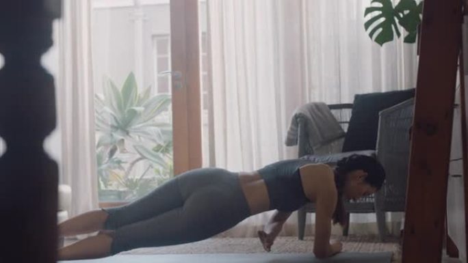 健康的亚洲女性在家锻炼，在客厅练习侧板，享受早晨健身锻炼