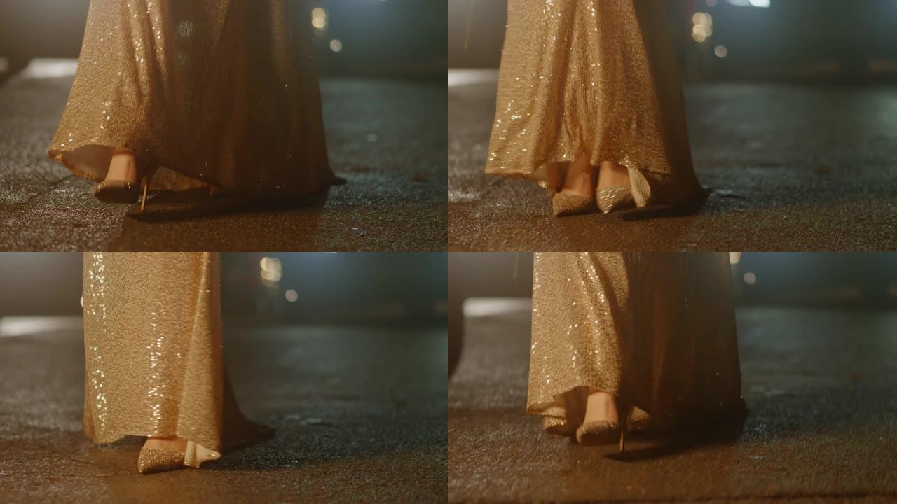 女人脚穿着豪华闪亮的金鞋和连衣裙在晚上慢慢走