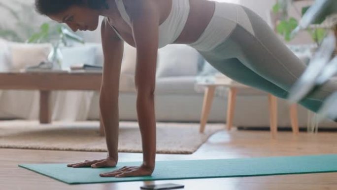 健康的年轻混血女子在家锻炼，在客厅练习木板，享受早晨健身锻炼4k