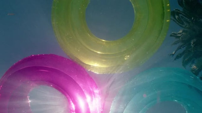 pov彩色游泳漂浮在游泳池多色充气水甜甜圈玩具与美丽的阳光照耀夏日水下视图pov 4k