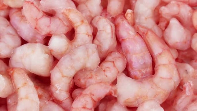 粉红色新鲜冷冻虾，带冰圈旋转。未煮熟的海鲜特写背景。冷冻对虾、美味佳肴、海鲜
