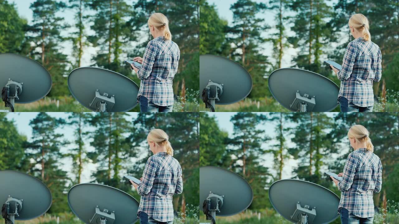 女人在户外调谐卫星天线，使用平板电脑。